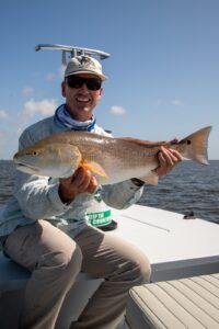 Angler holding a bull redfish caught on fly near Port O'Connor, Texas